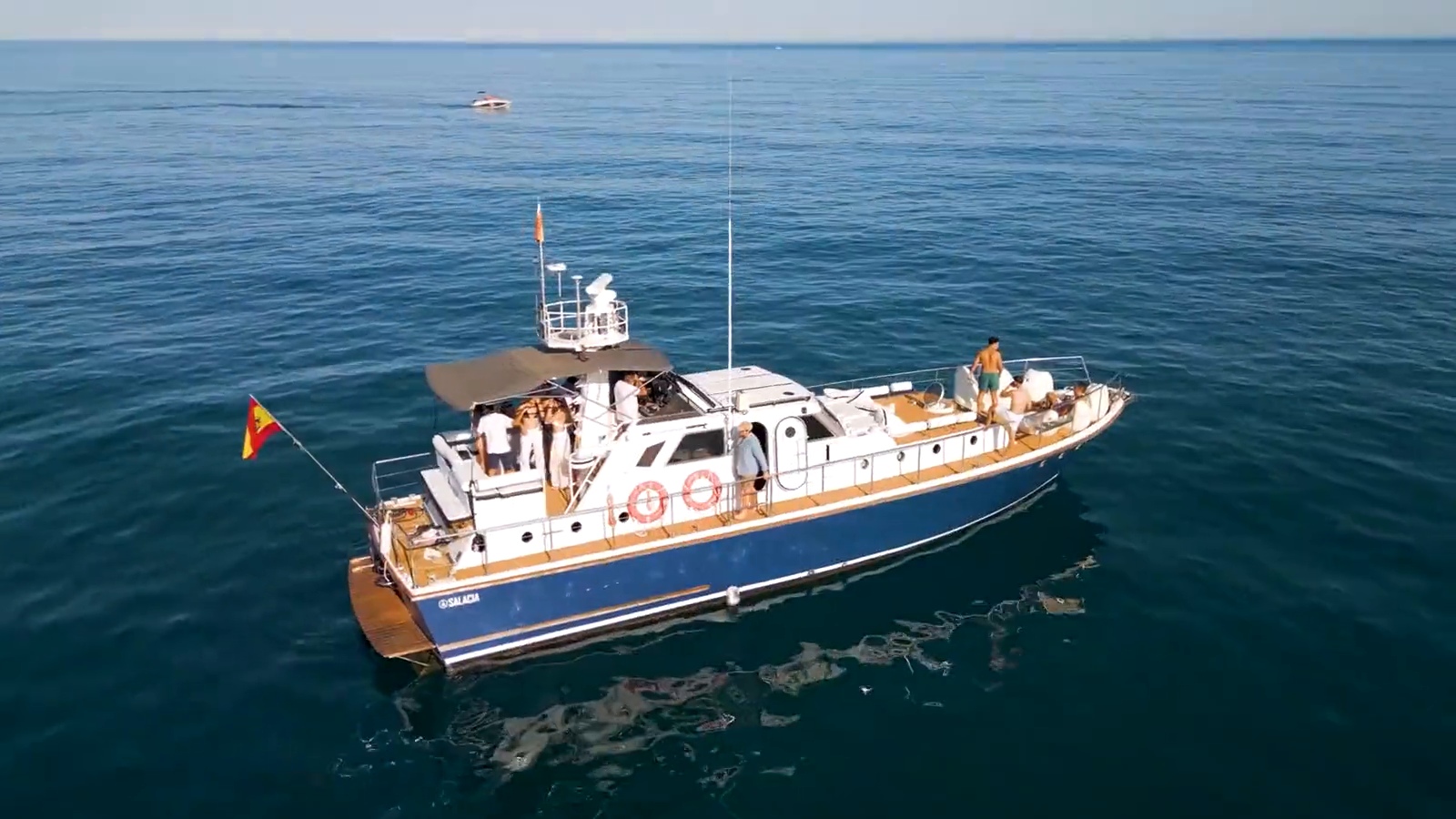 El SALACIA real navegando: casco azul, cabina blanca y cubierta de madera